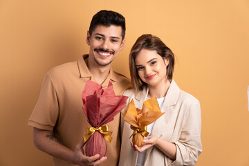joyful couple showing easter egg in beige background. holiday, easter, celebration concept.