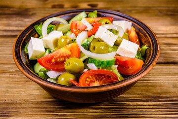 Ceramic plate with greek salad on wooden table
