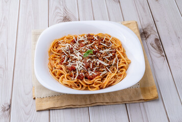 Spaghetti pasta on a plate with bolognese sauce, basil and parmesan cheese