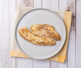Grilled tilapia or saint peter on a plate isolated over wooden table