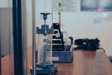 A laboratory setup featuring a transparent impact testing apparatus on a wooden table, used for scientific and engineering experiments.