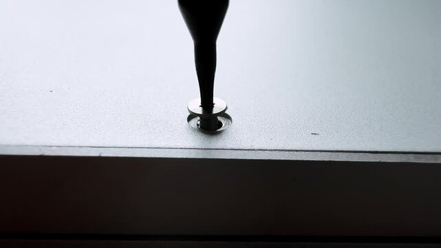 Unscrewing small screw with magnetic screwdriver tool, repairing of broken silver laptop.