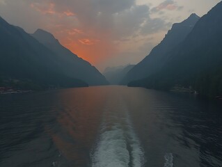 A scenic landscape of water and towering mountains during sunset