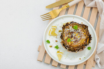 Delicious baked artichoke with parmesan cheese and pistachio. Olive oil, garlic, parsley and lemon