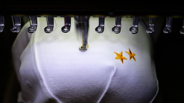 Machine embroidery of stars on a white hat with orange thread. Embroidered baseball cap close-up. 4k 50 fps video.