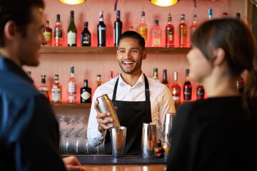 Young hispanic male bartender mixing drinks in a vibrant bar setting