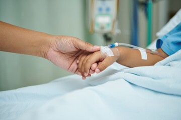 Supportive touch: adult hand holding child's hospitalized hand in medical setting