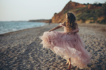 Beautiful woman. In the rays of the setting sun on the seashore a happy woman in a beautiful dress