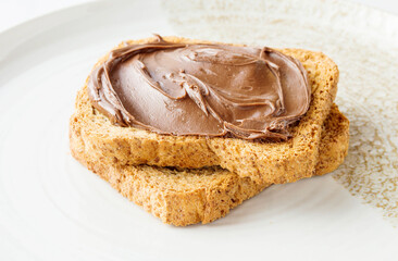 Spreading sweet chocolate cream onto toast on table.