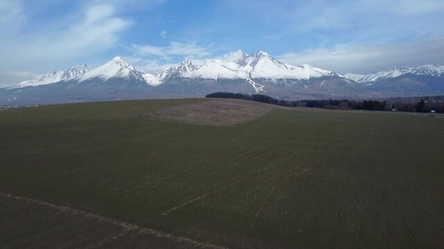 Aerial view of snowy Lomnicky stit and Slavkovsky stit peaks in the High Tatras from fields near Velka Lomnica, Slovakia