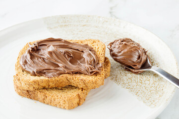 Spreading sweet chocolate cream onto toast on table.