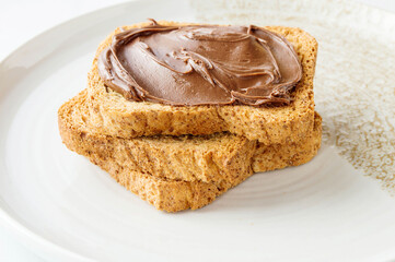 Spreading sweet chocolate cream onto toast on table.