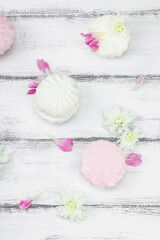 Fruit marshmallow with fresh flower petals on white wooden background. Lactose free vegan dessert