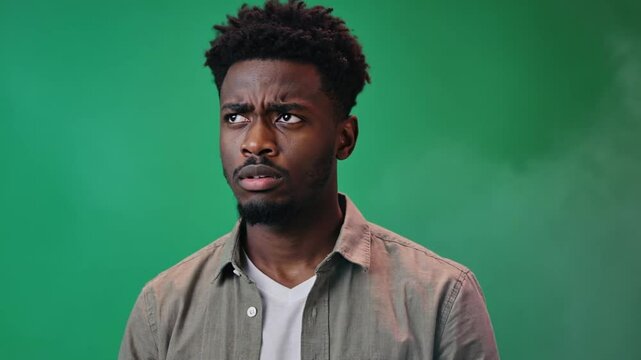 Curiosity and Concern: A portrait of a man, with a furrowed brow and attentive eyes, expressing a sense of contemplation and perplexity against a soft, green backdrop.
