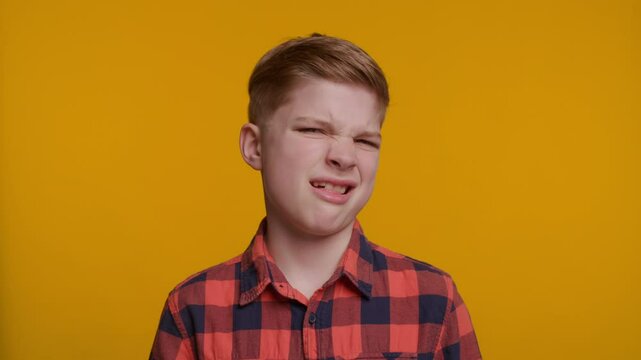 Young Boy Making a Disgusted Expression on Yellow Background