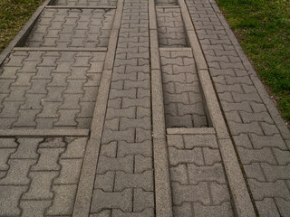 Concrete pavement with special grooved tracks designed for car wheels, typically used in eco-friendly or grass-integrated parking zones. Functional urban infrastructure in a geometric pattern