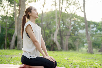 Obraz premium Young Asian woman doing yoga in the garden. Relaxing and healthy lifestyle concept.