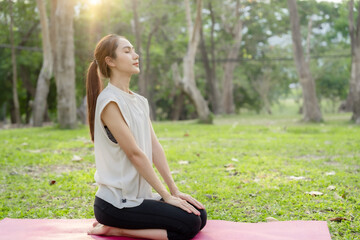 Young Asian woman doing yoga in the garden. Relaxing and healthy lifestyle concept. © Dara-Sroi