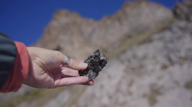 Women hand hold a stone with mountain on background