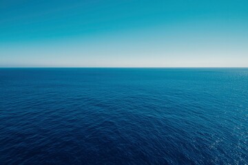 Obraz premium Vast expanse of deep blue sea meets a serene, light blue sky at the distant horizon line