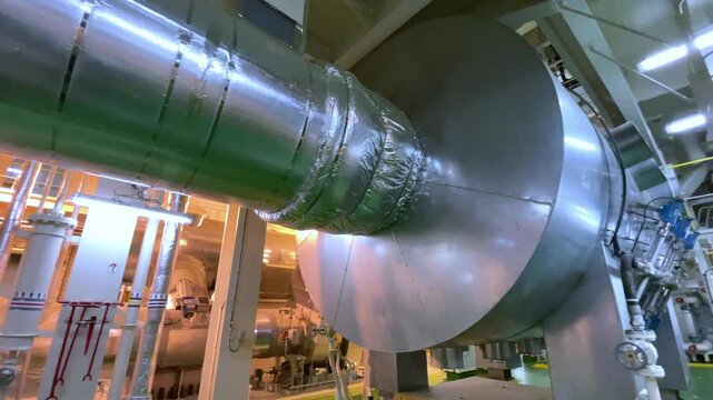 A large marine diesel engine stands in the ships engine room, surrounded by pipes, gauges, and controls, ready to power the vessel.
