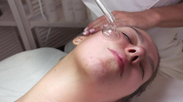 Young woman receiving hydra facial treatment for exfoliation, rejuvenation and hydration of her face skin. Modern facial hydro micro dermal abrasion peeling beauty procedure. Hydra vacuum cleaner.