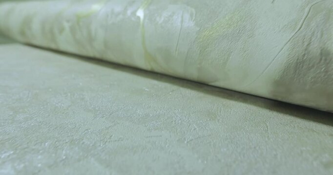 World of Wallpaper. Wallpapers Designs and Trends. Close-up of a roll of vinyl wallpaper on a table. Abstract drawing on vinyl wallpaper spread on the exhibition table. Close-up, macro photography.