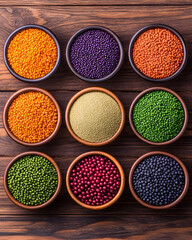 Nine bowls of colorful lentils and grains on wood