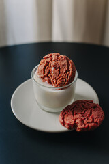 Tender white candle decorated with sweet cookies on a dark table.