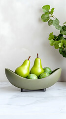 Olive green bowl holds pears and plums on marble