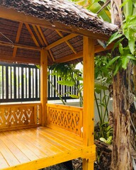 a wooden gazebo or pavilion. The structure has a thatched roof, wooden beams, and decorative...