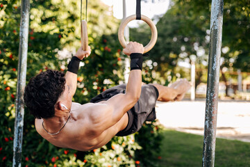 Obraz premium Strong young sportsman doing calisthenics at outdoor gym