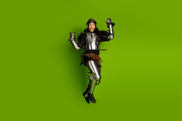 Obraz premium Portrait of a young knight in full armor expressing joy on a green background