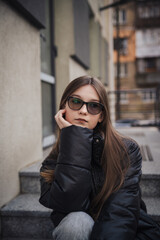 Fototapeta premium Stylish young woman in a black jacket on a city street on a cool day