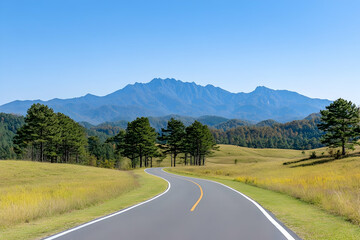 Scenic winding road through autumnal meadow towards majestic mountains under a clear blue sky