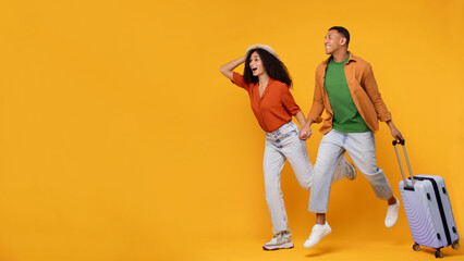 Travel ad. Excited African American couple running with luggage and looking at copy space on orange...
