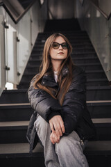 Stylish young woman in a black jacket on a city street on a cool day