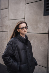 Obraz premium Stylish young woman in a black jacket on a city street on a cool day