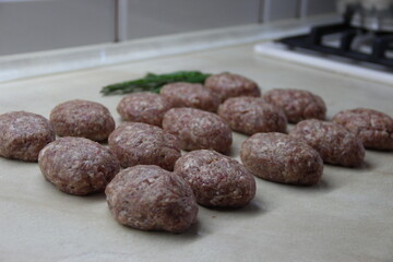 Homemade meatballs of pork and beef, arranged in lines on the table chili pepper and rosemary