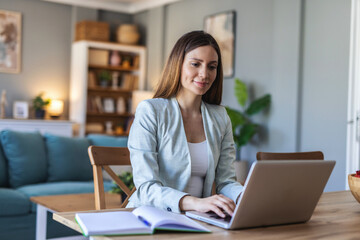 Woman working on laptop in modern home office setting. Young woman in casual attire working on a laptop in a stylish home office environment. Focused and productive atmosphere.
