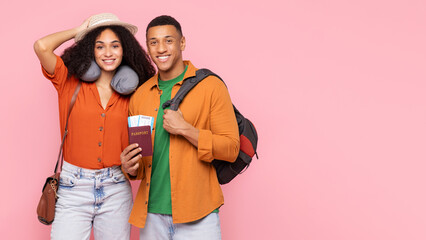 Obraz premium Happy black couple with passports and backpack posing over pink studio background, smiling at camera, ready for trip, panorama with free space