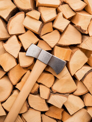 Fototapeta premium Neat Stacking: An axe rests atop a perfectly stacked pile of freshly split firewood. Capturing the essence of preparation, warmth, and rustic charm.