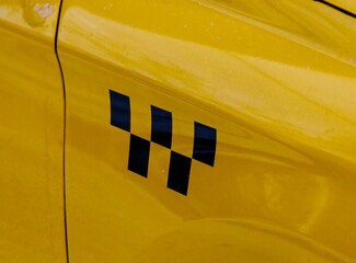 Bright yellow taxi car showcasing distinctive checkered pattern in a bustling urban environment...