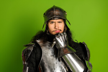 Costumed individual wearing metallic armor against vibrant green backdrop illustrating medieval...