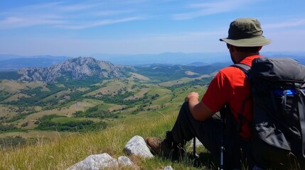 Hiker Contemplating Scenic Mountain View from Summit Overlooking Lush Green Valleys