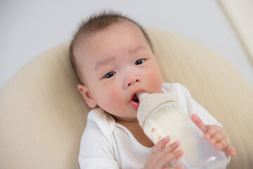  Infant holding bottle while drinking fresh milk