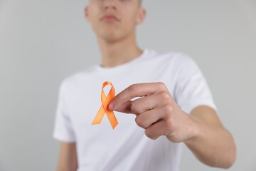 Multiple Sclerosis awareness. Man with orange ribbon on light grey background, closeup