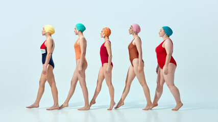 Women in vintage swimsuits and swim caps walking in line in rhythmical motion over light blue...