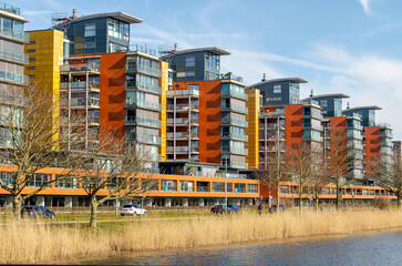 Barendrecht, The Netherlands, March 6, 2025: colorful residential towers overlooking a lake lined...