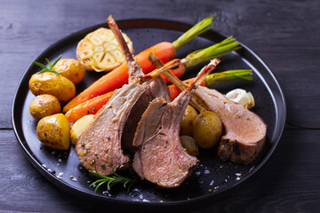 Roasted rack of lamb. Lamb chops with vegetables on black plate